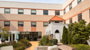 Wide view of the courtyard at Commonwealth Senior Living at North Byron in Wyoming, Michigan, showing the repainted EIFS exterior with three-color matching and the preserved chapel structure, completed by Vork Brothers Painting.
