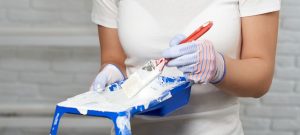 female hands holding paint tray and brush