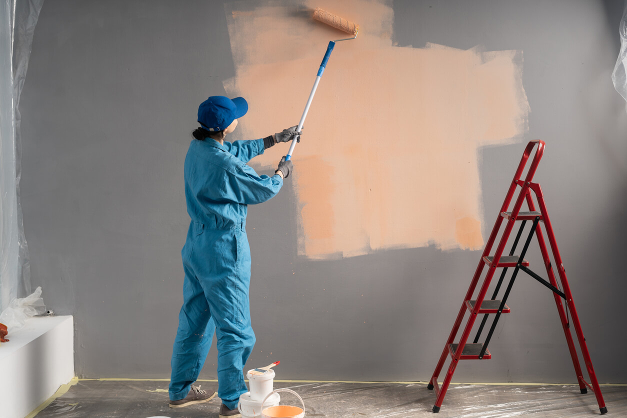 Paints walls with long painting roller