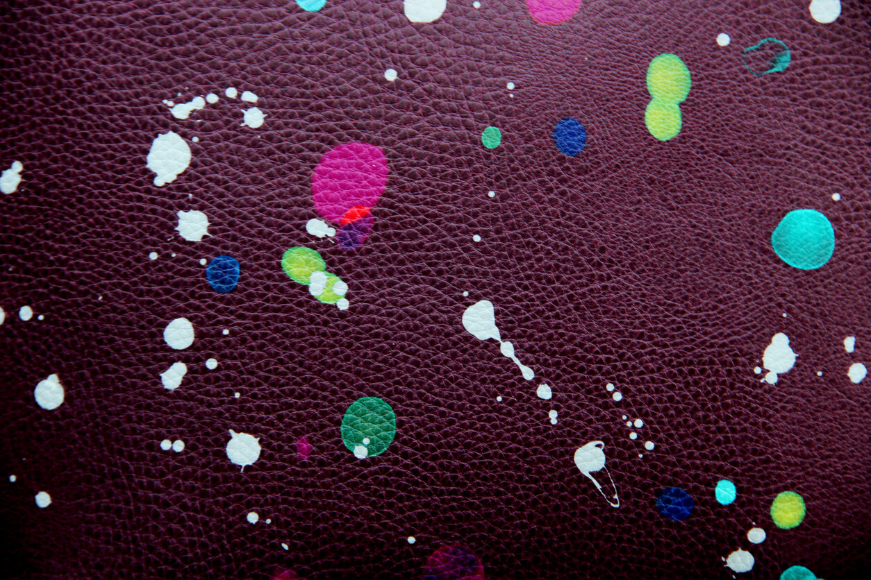 Colored paint drops, purple leather background