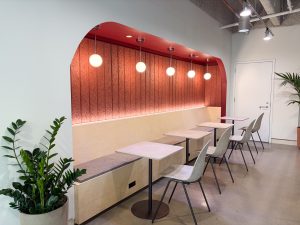 Custom coworking seating area featuring painted acoustic paneling, integrated lighting, and bold architectural accent colors designed to create a modern collaborative workspace.