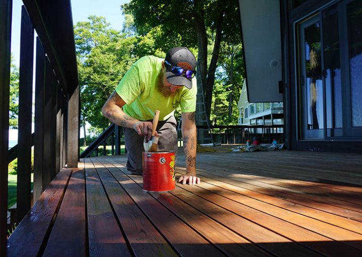 Vork Brothers team member painting an outdoor deck of residential home