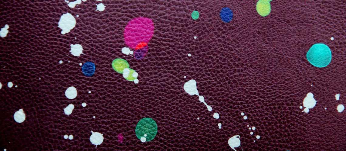 Colored paint drops, purple leather background