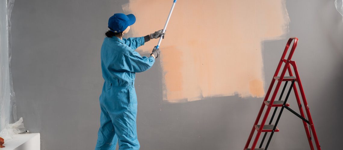 Paints walls with long painting roller